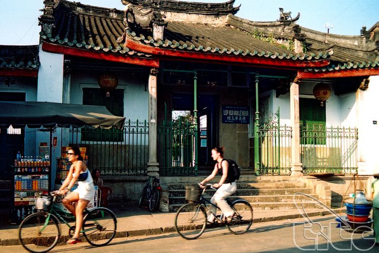Deux personnes à vélo dans une rue calme de Hoi An, illustrant une expérience de voyage détendue pour un Vietnam du Nord au Sud en 2 Semaines.