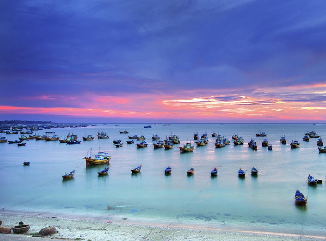 Bateaux de pêche traditionnels amarrés dans la baie de Mui Ne au crépuscule dans un itinéraire Vietnam 10 jours.
