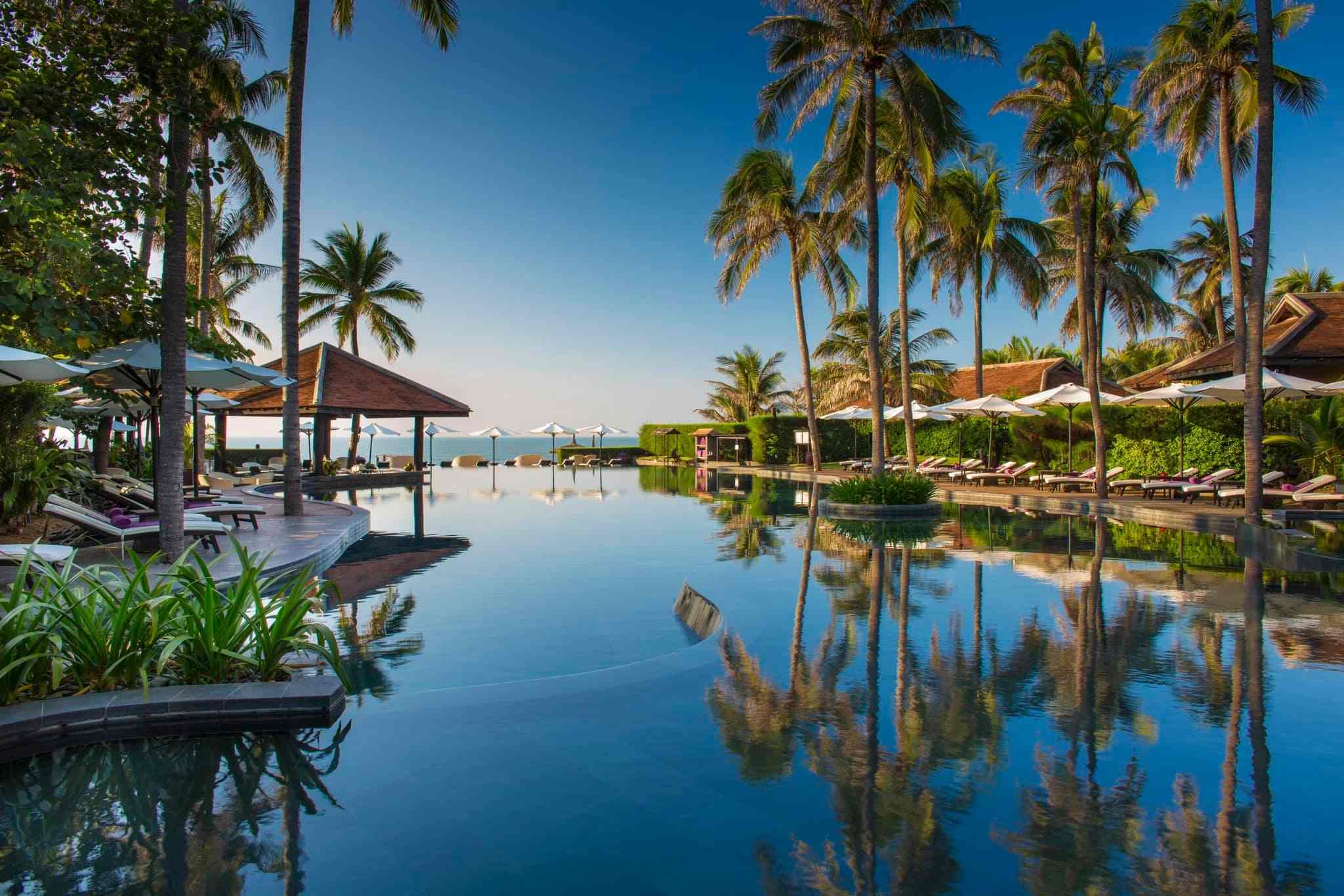 Piscine à débordement bordée de palmiers dans un resort de luxe à Mui Ne, conclusion idéale d'un itinéraire Vietnam 10 jours.