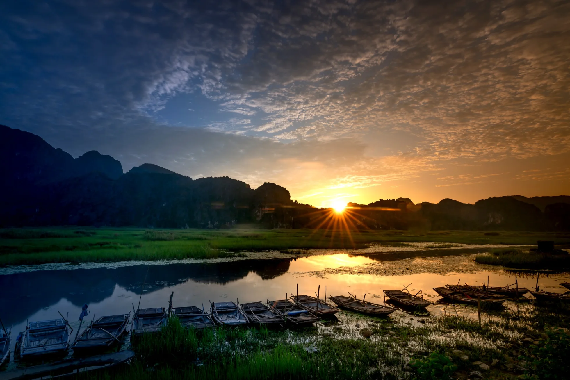 Visiter le Vietnam en 10 jours au rythme paisible d'un coucher de soleil sur les barques traditionnelles à Ninh Bình.