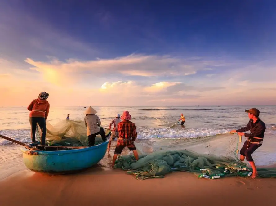 Pêcheurs et barque ronde sur la plage de Làng Lò au lever du soleil lors d'un circuit Vietnam sur mesure