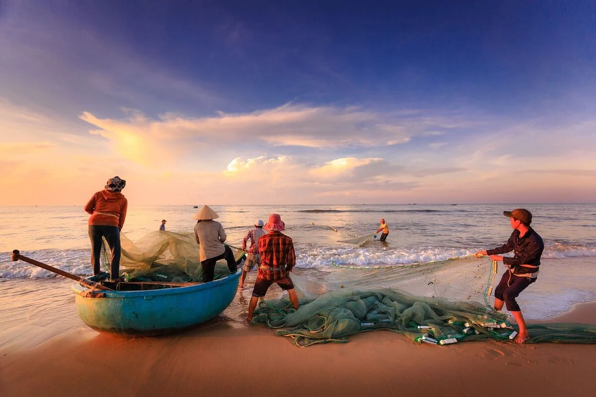 Pêcheurs et barque ronde sur la plage de Làng Lò au lever du soleil lors d'un circuit Vietnam sur mesure