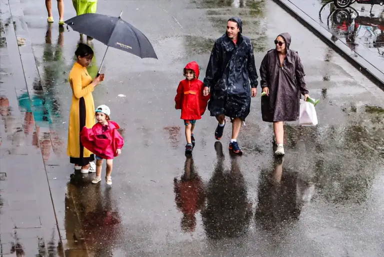Une famille avec de jeunes enfants marchant sous la pluie avec des imperméables lors d'un circuit au Vietnam en famille