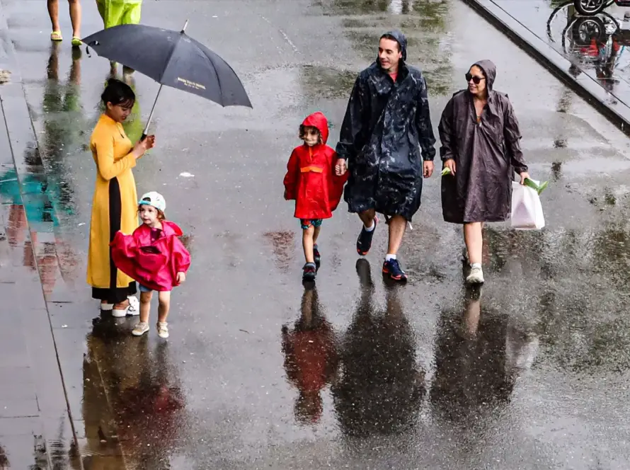 Une famille avec de jeunes enfants marchant sous la pluie avec des imperméables lors d'un circuit au Vietnam en famille