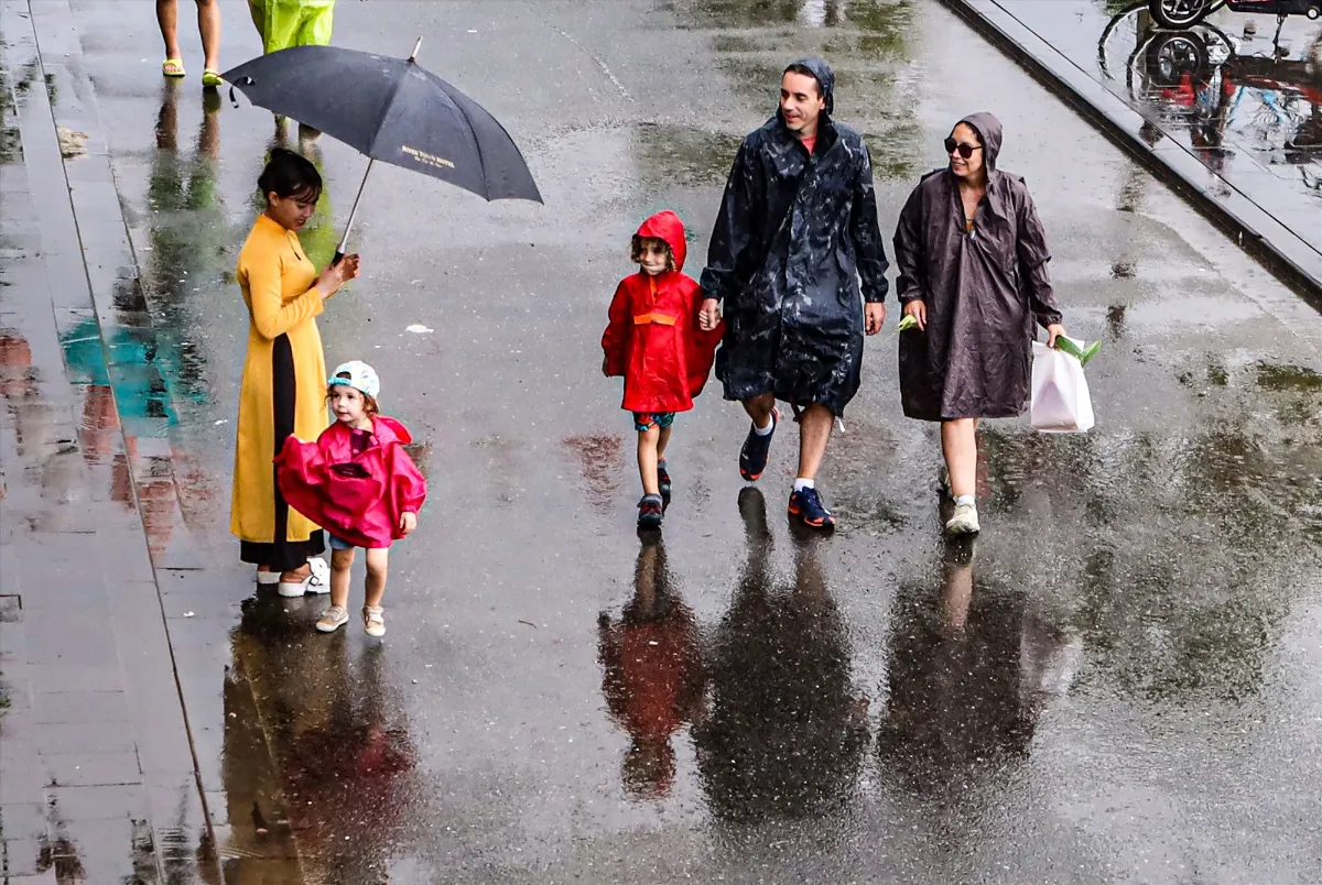 Une famille avec de jeunes enfants marchant sous la pluie avec des imperméables lors d'un circuit au Vietnam en famille
