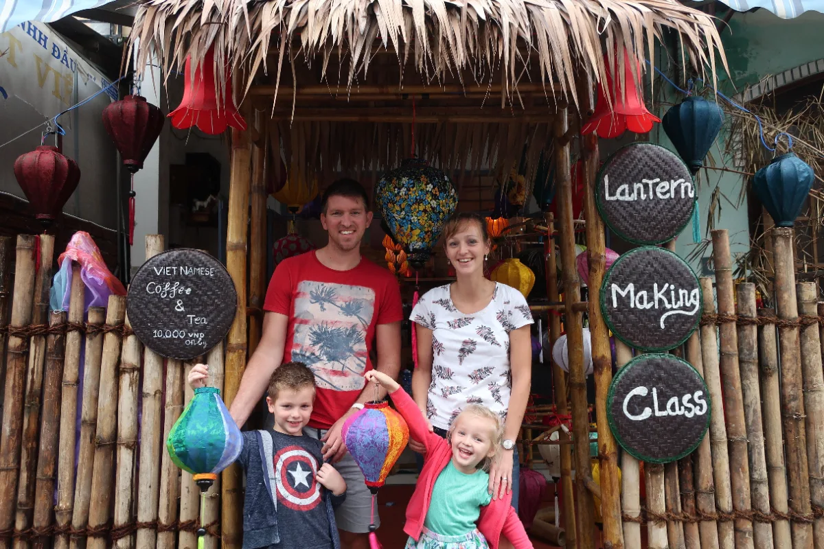 Une famille avec deux jeunes enfants montrant leurs créations artisanales après un atelier de lanternes lors d'un circuit au Vietnam en famille