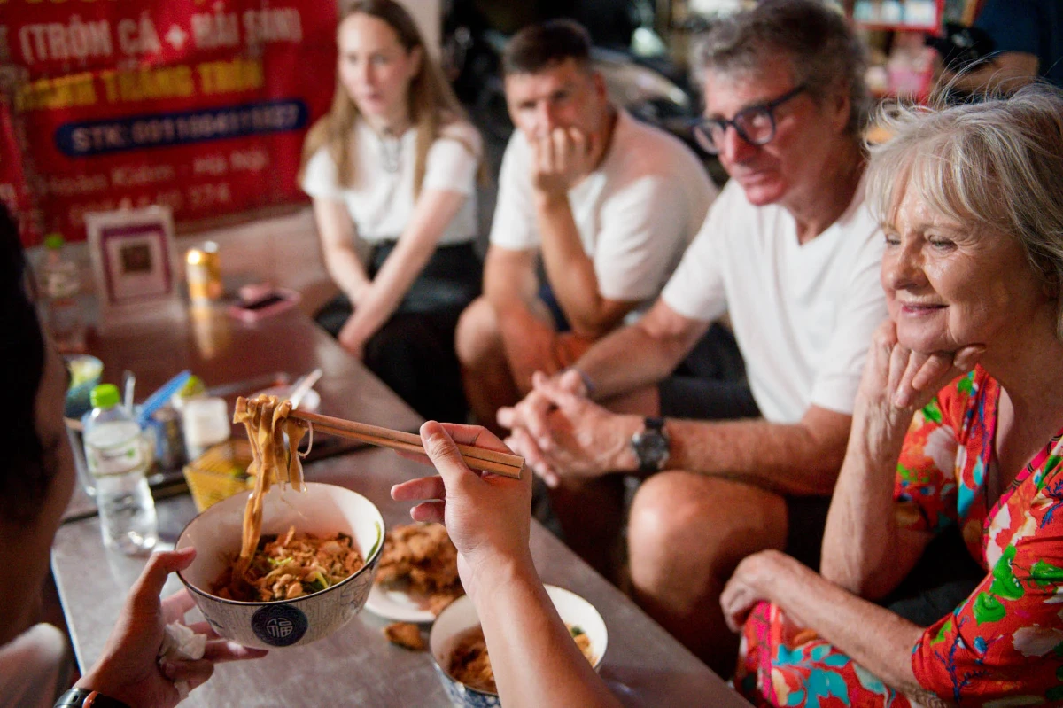 Un groupe de voyageurs attentifs lors d'une dégustation dans une échoppe de quartier à Hanoi, une expérience comprise dans le prix voyage Vietnam 12 jours