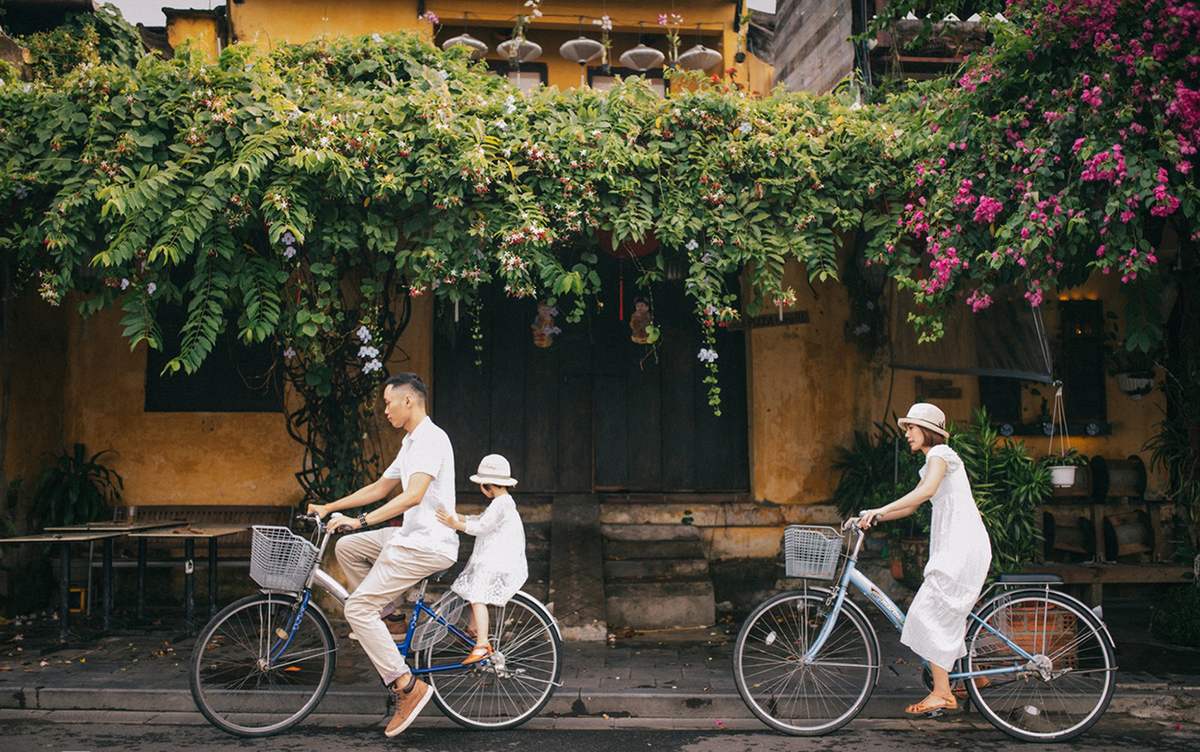 Parents et enfant à vélo dans les ruelles paisibles de Hoi An lors d'un voyage au Vietnam en famille